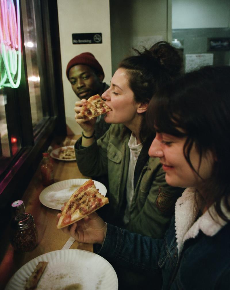 Friends sharing pizza at a counter